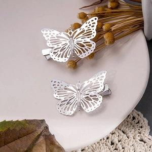 Deux pinces à cheveux papillon en argent ajouré sur assiette avec fleurs séchées