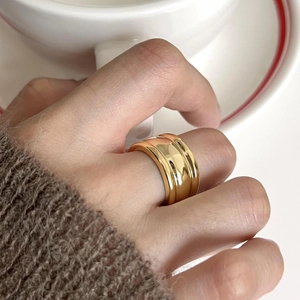 Close-up of a wide triple-layer gold ring with a polished finish worn on a finger