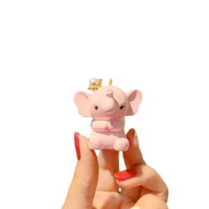 Pink elephant keychain with golden crown and pearl accessory shown in a hand close-up