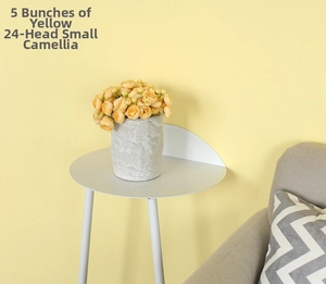 Close-up of five bundles of yellow artificial camellias in a gray vase on a side table