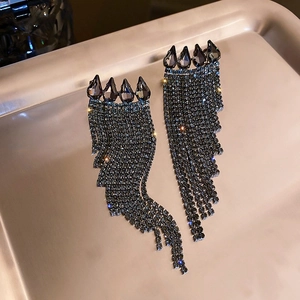 Gros plan de boucles d'oreilles à pompons gris foncé avec strass en cascade