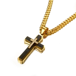 Detail of layered gold and black cross pendant with small diamonds on cuban chain