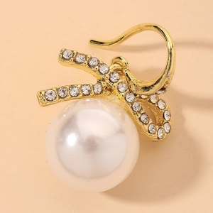 Close-up of golden bow earrings with sparkling rhinestones and white pearls