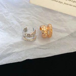 Detail of gold and silver double-layered ear cuffs with hammered metal texture