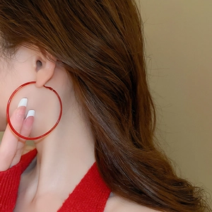 Detail view of a large red hoop earring worn by a model for a modern minimalist style