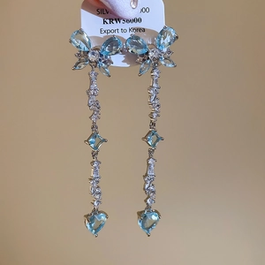 Detail of silver long tassel earrings with light blue butterfly and heart zircon stones