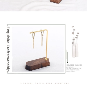 Detailed close-up of gold geometric drop earrings on a walnut wood jewelry display stand