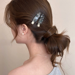 Detail view of rhinestone waterdrop hair clips and pearl earrings on a model