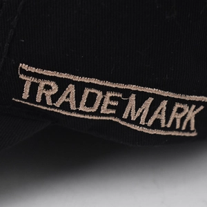 Makroaufnahme des 3D-gestickten TRADEMARK-Textes auf einer schwarzen Baseballkappe