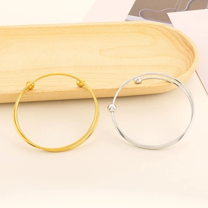 Detail of minimalist double-layered open bangles in gold and silver finish with metal beads