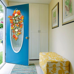 Detail showing artificial fall wreath with white pumpkins and maple leaves on a blue door