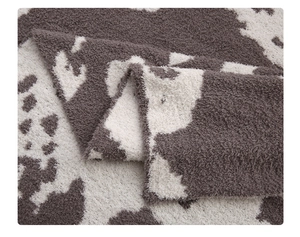 Close-up of thick plush cow print blanket showing soft brown and white fuzzy texture