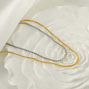 Elegant gold and silver twisted rope chain necklaces displayed on floral relief plate