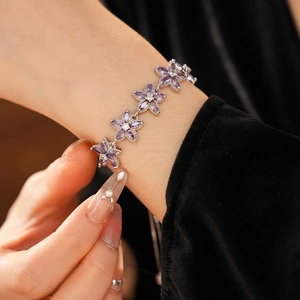 Nahaufnahme eines silbernen Armbands mit violetten Zirkonia-Blüten am Handgelenk