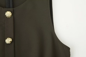 Detailed view of olive green midi dress featuring golden relief buttons and woven fabric texture