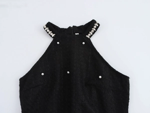 Détail d'une robe noire dos nu en tweed avec motifs floraux en perles et strass