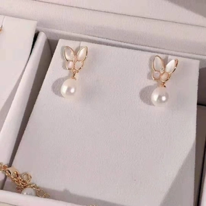 Elegant butterfly shell pearl drop earrings set in rose gold finish on display