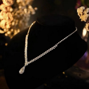 Close-up of sparkling rhinestone teardrop pendant necklace on a black mannequin bust