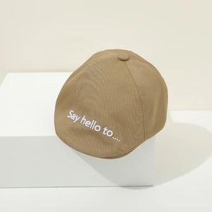 Detailed shot of khaki cotton baby newsboy cap with white Say hello embroidery