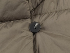 Macro view of dark olive quilted jacket with marble-textured button and precise stitching