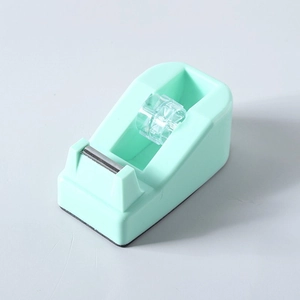 Macro detail of mint green tape dispenser with sharp metal blade and clear plastic core spool