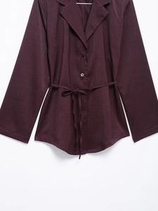 Close-up of wine red satin blouse featuring a tailored waist tie and elegant fabric texture