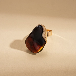Détail d'une bague dorée vintage ornée d'une pierre en résine ambrée marron en goutte
