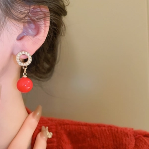 Close-up of vintage hoop earrings with pearls and a glossy red bead on a model