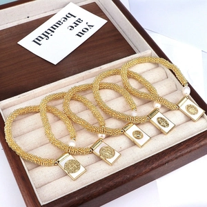 Macro shot of gold beaded bracelets with white pearls and religious medallions in a box