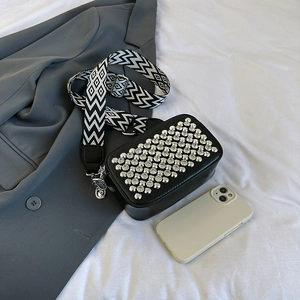 Black rivet crossbody square bag with trendy patterned wide strap on a clean white background