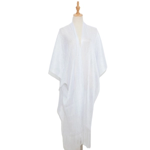Detailed view of white knit shawl fabric featuring metallic threads and long fringe tassels