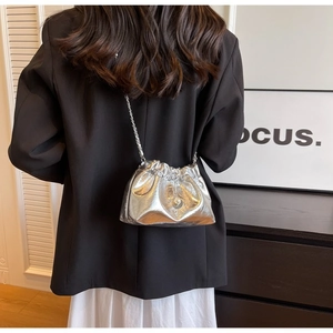 Detail of silver drawstring bucket bag with metallic finish and metal chain strap