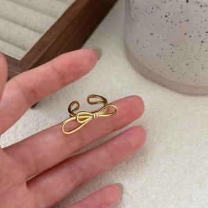 Close-up of golden bow-shaped adjustable ring in polished finish on finger