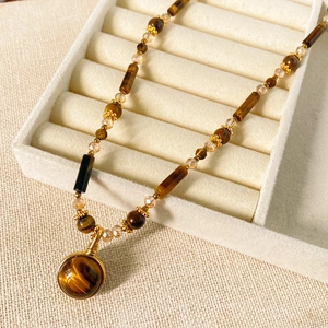 Detail of beaded necklace with tiger eye stone pendant in a velvet jewelry box