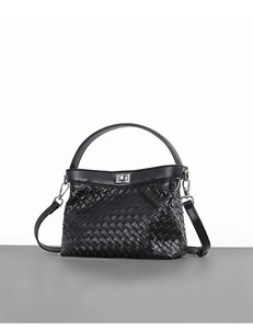 Detail of black woven leather handbag showing silver hardware and intricate texture