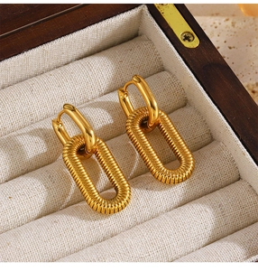 Macro detail of 18K gold-plated oval hoop earrings with textured spiral design