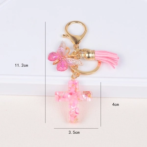 Detailed view of pink resin cross keychain with dried petals, gold leaf and tassel