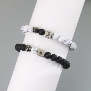 Detail of sun and moon symbols on black and white marble beaded couple bracelets