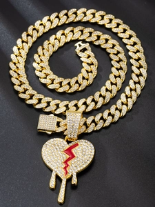 Macro detail of iced-out gold Cuban chain and dripping broken heart pendant with red stones