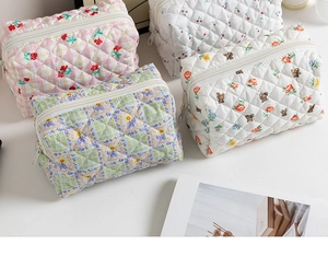 Detailed view of four assorted floral quilted makeup bags with zippers on white surface