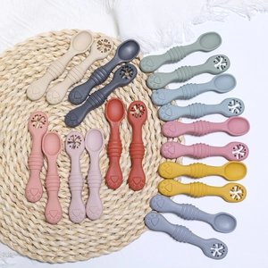 Flat lay of colorful baby silicone training spoons with textured teether ends in various shades