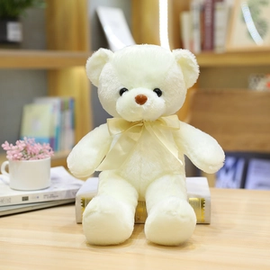 Lindo oso de peluche crema con cinta amarilla sentado sobre libros para regalo