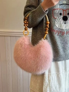 Pink faux fur hobo bag with wooden bead handle and golden rings on white background