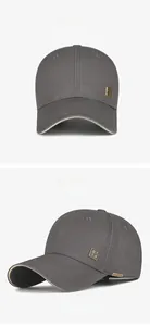 Detailansicht der dunkelgrauen Baseballkappe mit quadratischem goldfarbenem Logo und Seitenetikett