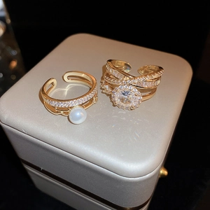 Dettaglio di un set di anelli multistrato placcati in oro con zircone e perla in scatola