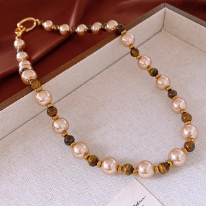 Détail de perles crème et œil de tigre brun avec fermoir à anneau plaqué or de luxe
