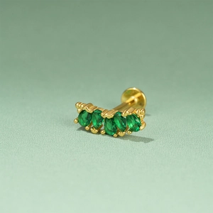 Detail of gold cartilage earring featuring curved marquise green zircon stones and flat back