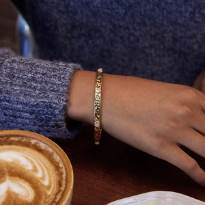 Detailed shot of an 18K gold stainless steel hammered bangle with round zircons