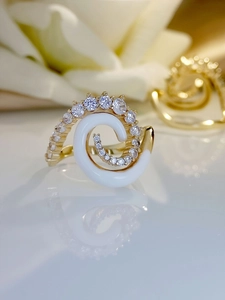 Macro shot of gold spiral ring with white enamel and sparkling zircon gemstone accents