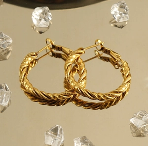 Macro shot of 18k gold plated stainless steel twisted rope hoop earrings on a mirror